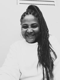 Portrait of smiling young woman against wall