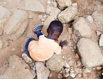 High angle view of boy sitting on rock