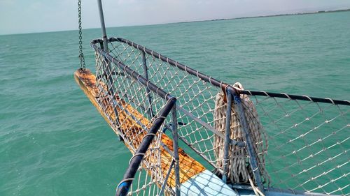 Fishing net on railing by sea against sky