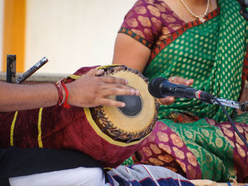 Midsection of man playing musical instrument by woman