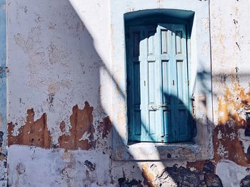Closed turquoise wooden door of old building with faded white color 