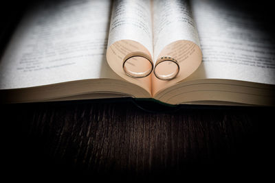High angle view of wedding rings amidst folded pages as heart shape on book