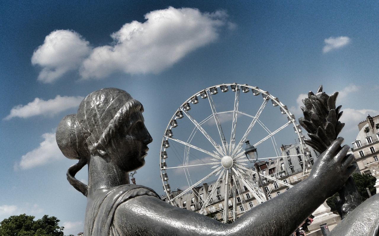 low angle view, amusement park, amusement park ride, ferris wheel, sky, arts culture and entertainment, cloud - sky, cloud, fun, metal, blue, large, tree, outdoors, built structure, cloudy, enjoyment, no people, day, circle