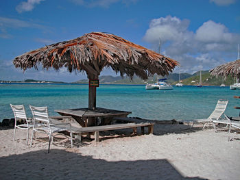 Deck chairs on beach against sky