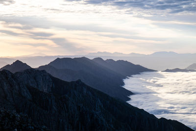 Distant view of mountain ridges at sunrise with sea of clouds 