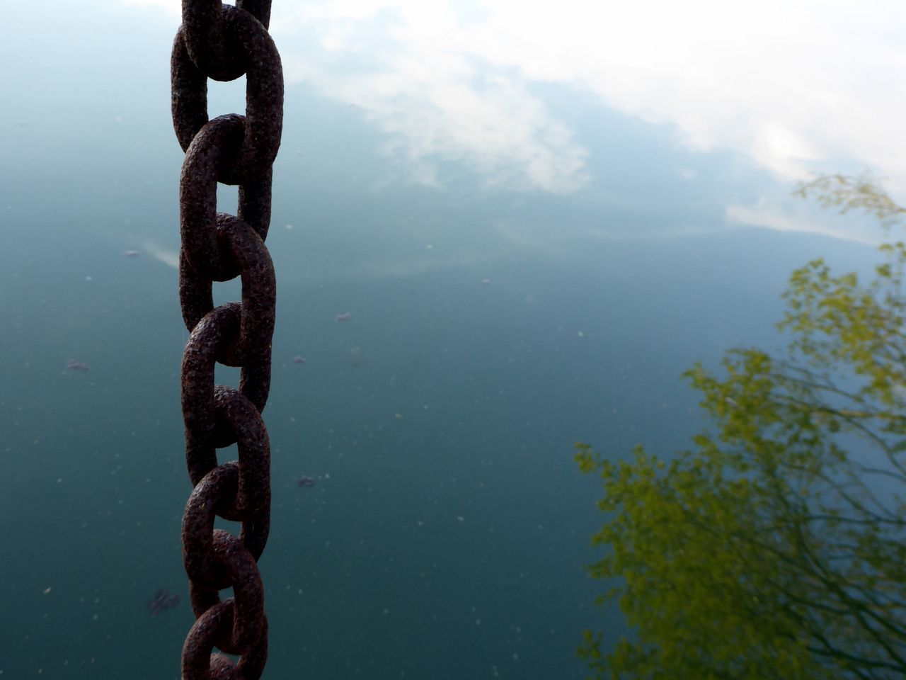 CLOSE-UP OF METAL CHAIN AGAINST LAKE