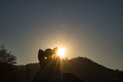 Silhouette person against bright sun at sunset