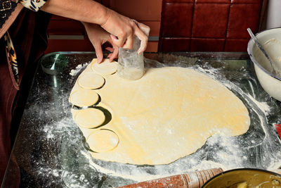 Female hands prepare dough blanks for sculpting ukrainian dumplings.