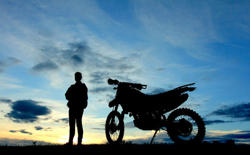 Silhouette man riding motorcycle against sky during sunset