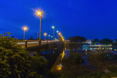 Illuminated bridge over river against sky at night