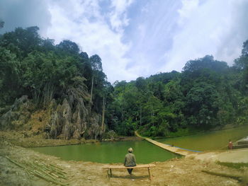 Man on riverbank against sky