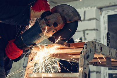 Cropped hand of manual worker cutting metal in factory