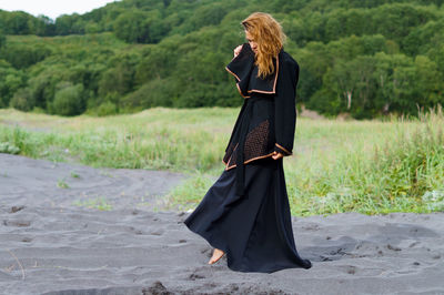 Mid adult woman wearing black dress at beach