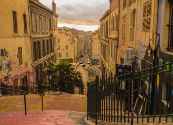 Street amidst buildings against sky during sunset