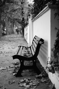 Empty bench in park against buildings