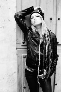 Portrait of young woman standing against wall