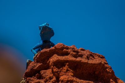 Low angle view of rocks against clear blue sky