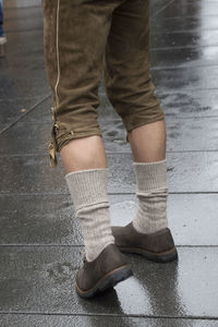 Low section of man standing on wet footpath