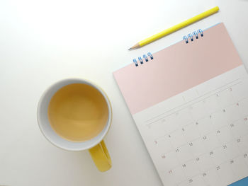 Directly above shot of tea cup and calendar on white background