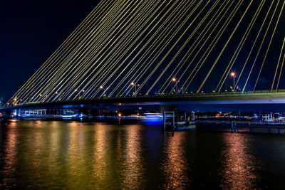 Illuminated bridge over river against sky at night