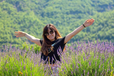Young woman with arms raised standing on field