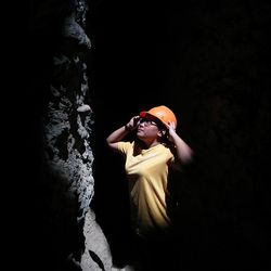 Woman looking away while standing against black background