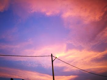 Low angle view of silhouette electricity pylon against sky during sunset