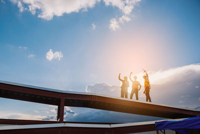 Low angle view of people at bridge against sky