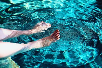 Low section of person swimming in pool