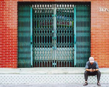 Man sitting against closed gate