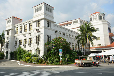 Road by buildings in city against sky