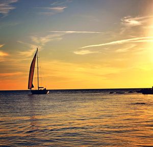 Silhouette sailboat in sea against sky during sunset