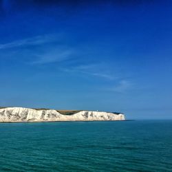 White cliffs of dover by sea against blue sky