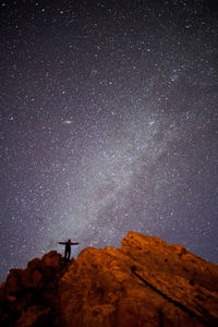 Silhouette man standing on mountain against star field at night