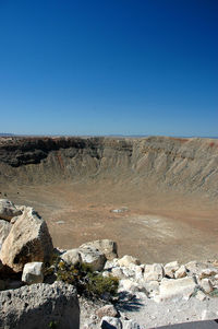 Rocks on land against clear blue sky