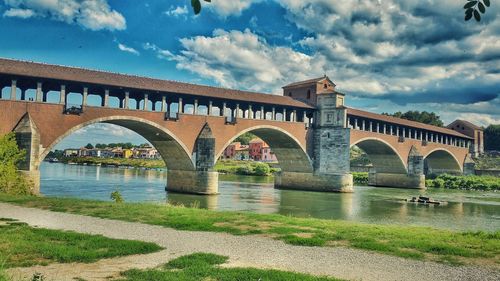 Bridge over river against cloudy sky