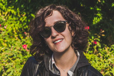 Close-up portrait of young woman wearing sunglasses against plants