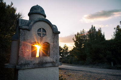 Close-up of illuminated cross against sky during sunset