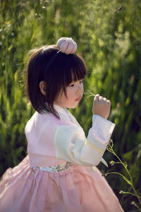 Korean national children pink costume on a four year old girl standing in a field with grass