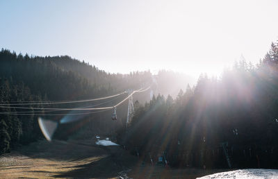 Panoramic view of winter forest and cable car against bright sun