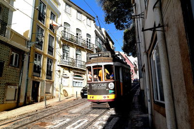 Cars on railroad tracks in city against sky