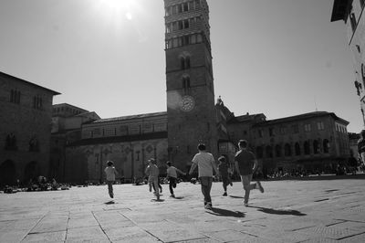 Rear view of boys running by pistoia cathedral