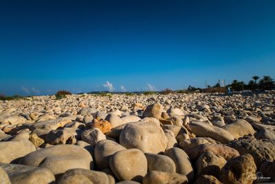 Rocks on shore against clear blue sky