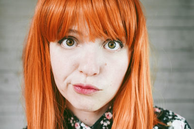 Close-up of redhead woman staring against wall