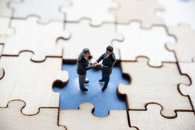 High angle view of figurines amidst wooden jigsaw puzzle