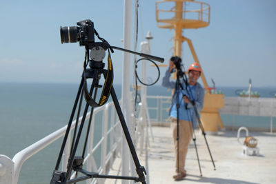 Man photographing metal structure against sky