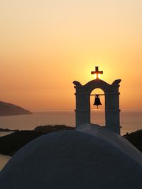 Cross on beach against sky during sunset