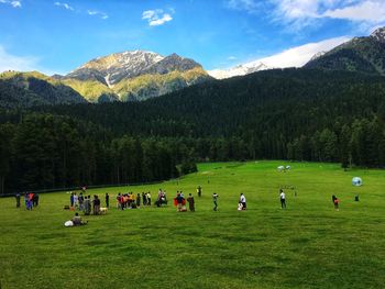 People on field against mountains