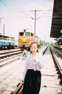 Young woman walking on railroad track during sunny day