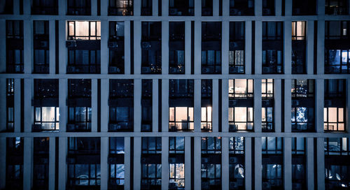 Blinking and flashing windows of the multi-storey building of glass and steel lighting inside. 